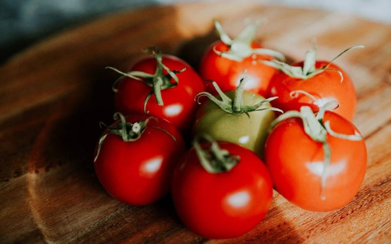 bunch of tomatoes on a wooden plate